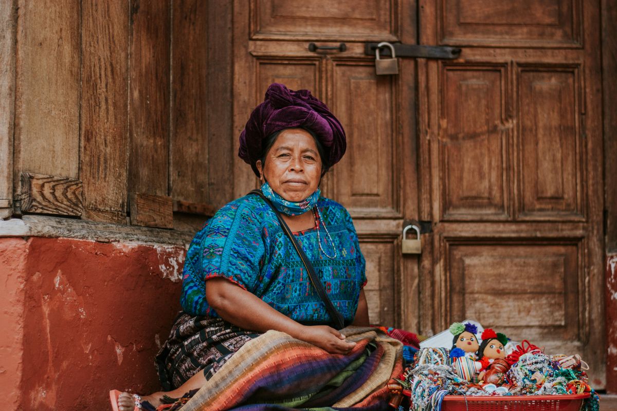 Vendedora guatemalteca mostrando artesanías y textiles hechos a mano