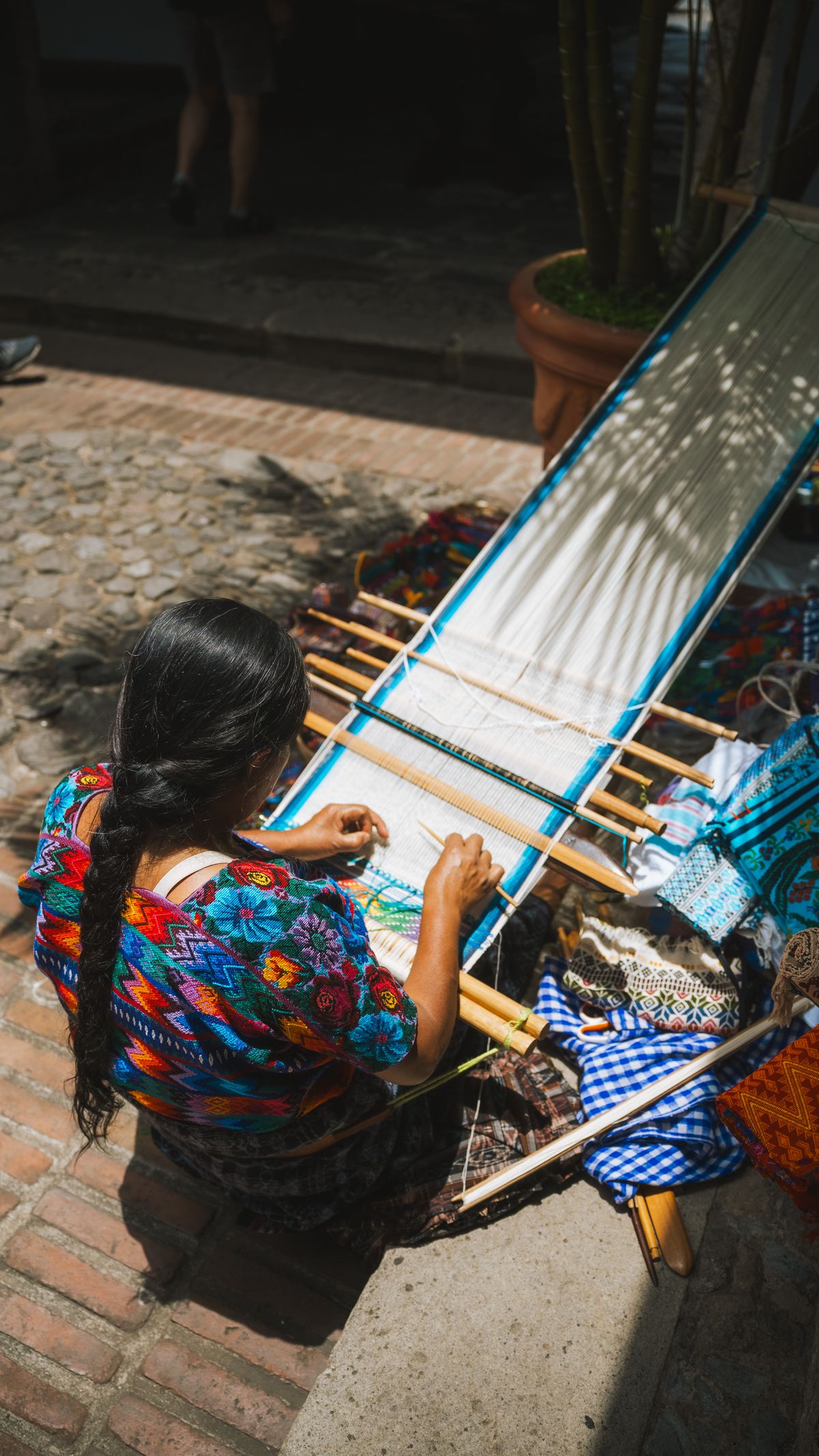 Mujer guatemalteca tejiendo textiles de colores en telar de cintura en Antigua